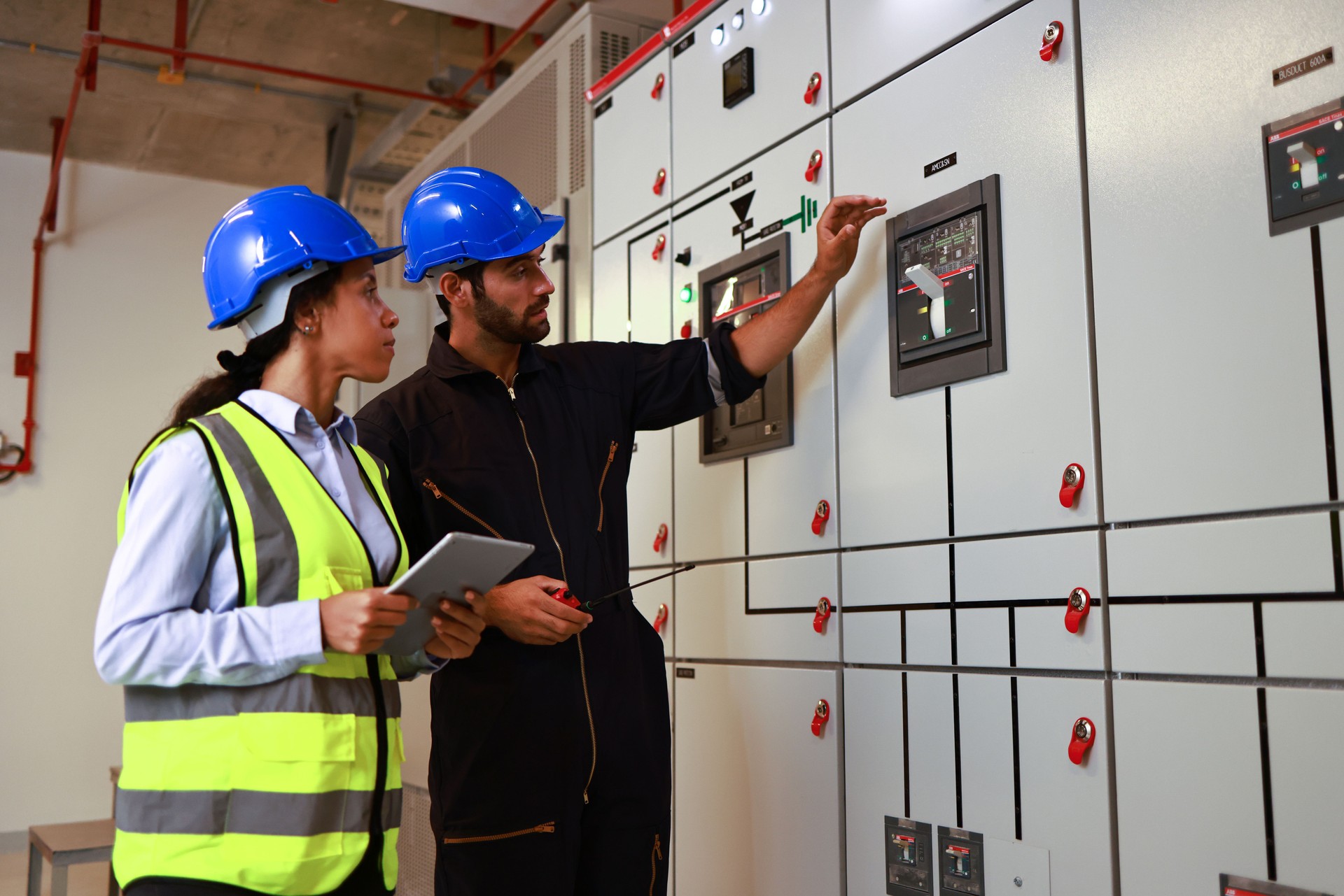 Male and Female colleague electrical engineer work checking at Electrical Distribution Control Room